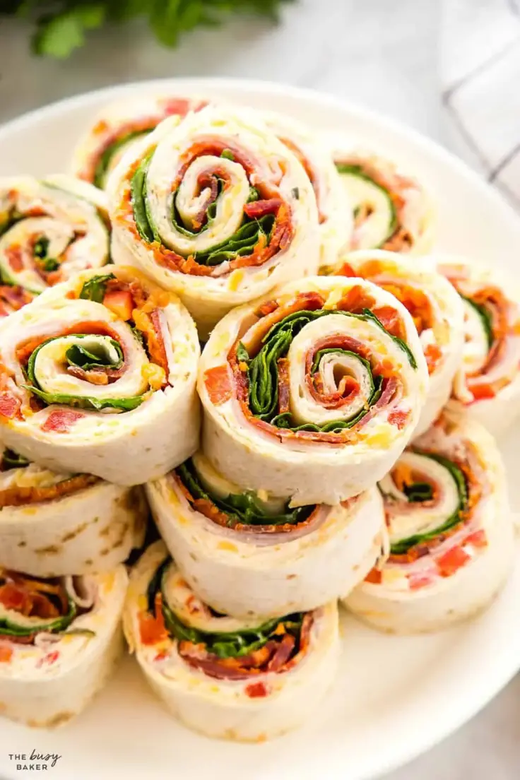 Easy Turkey Pinwheels Appetizers are made with tortillas, turkey deli meat, sliced pepperoni, bell peppers, ranch seasoning, and a couple handfuls of baby spinach leaves. 